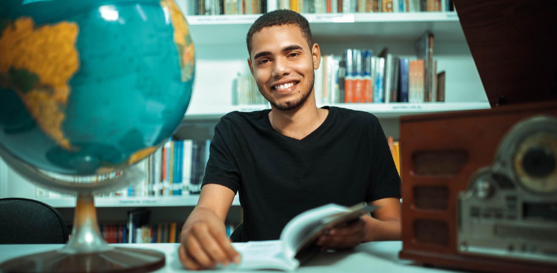 Aluno UNIPAM abrindo um livro e sorrindo